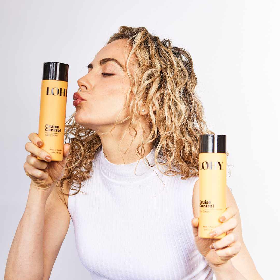 Blonde curly girl holding bottles of curl cream