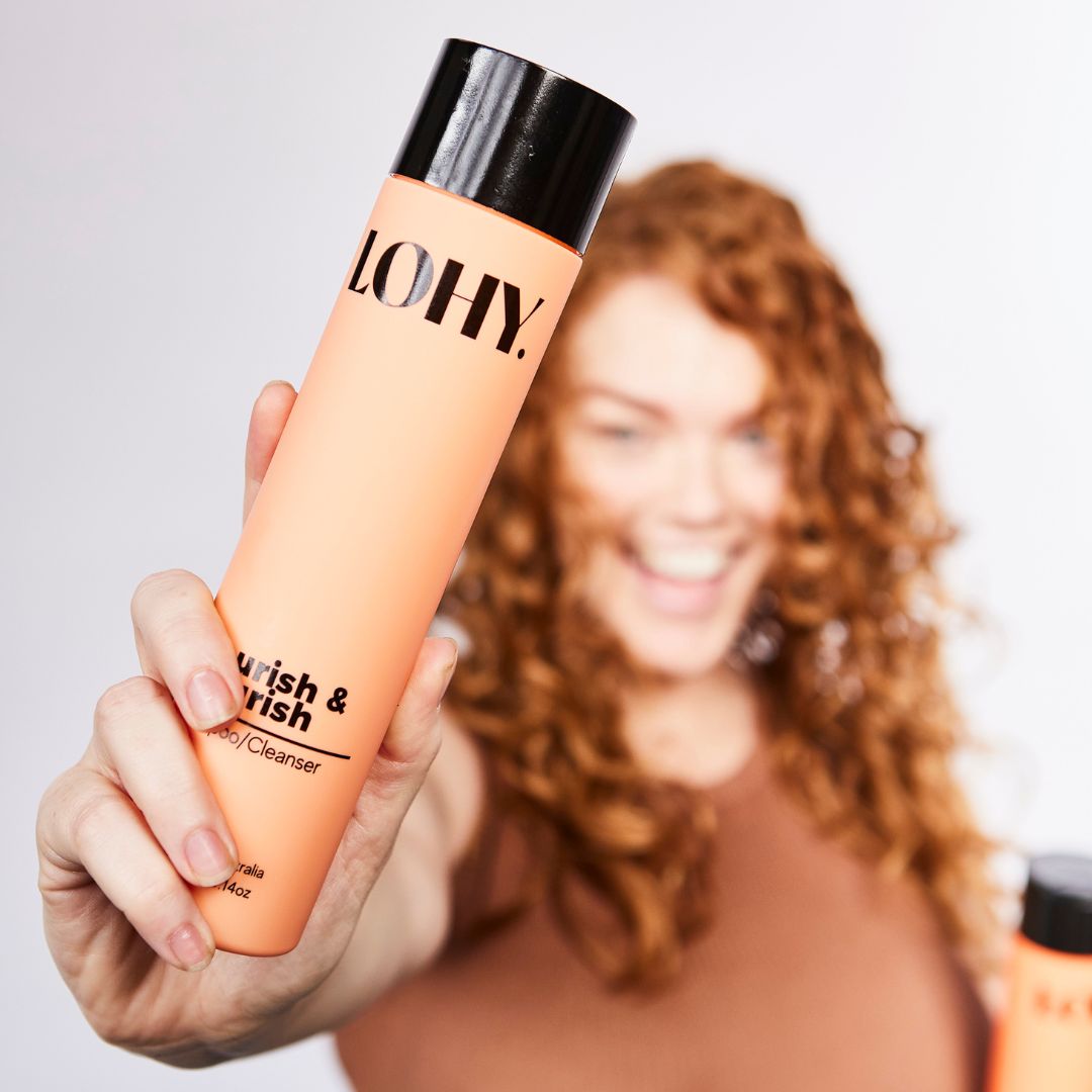 Red head holding curly hair shampoo