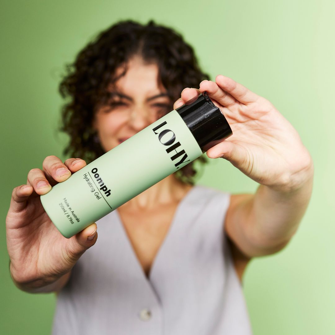Person holding a bottle of Oomph hydrating gel on a bright green background