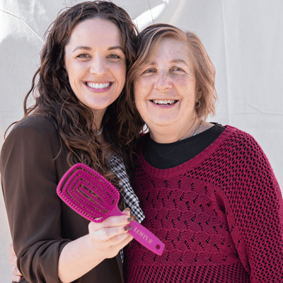 Jonina and her mum smiling and holding pink paddle brush