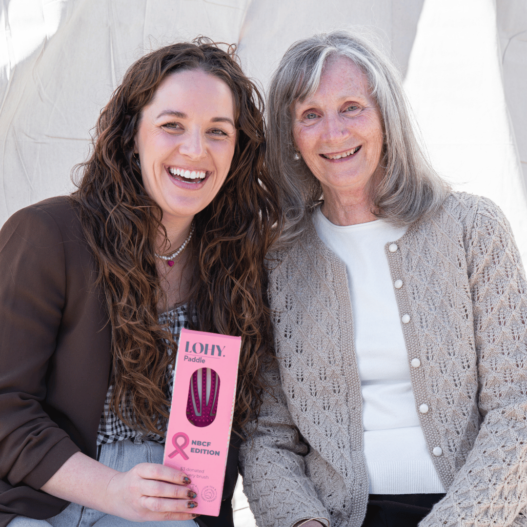 two ladies smiling holding LOHY. pink paddle brush