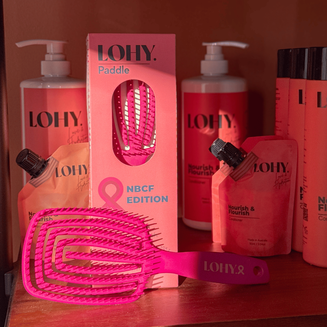 LOHY. pink paddle brush sitting on shelf with LOHY. shampoo and conditioner