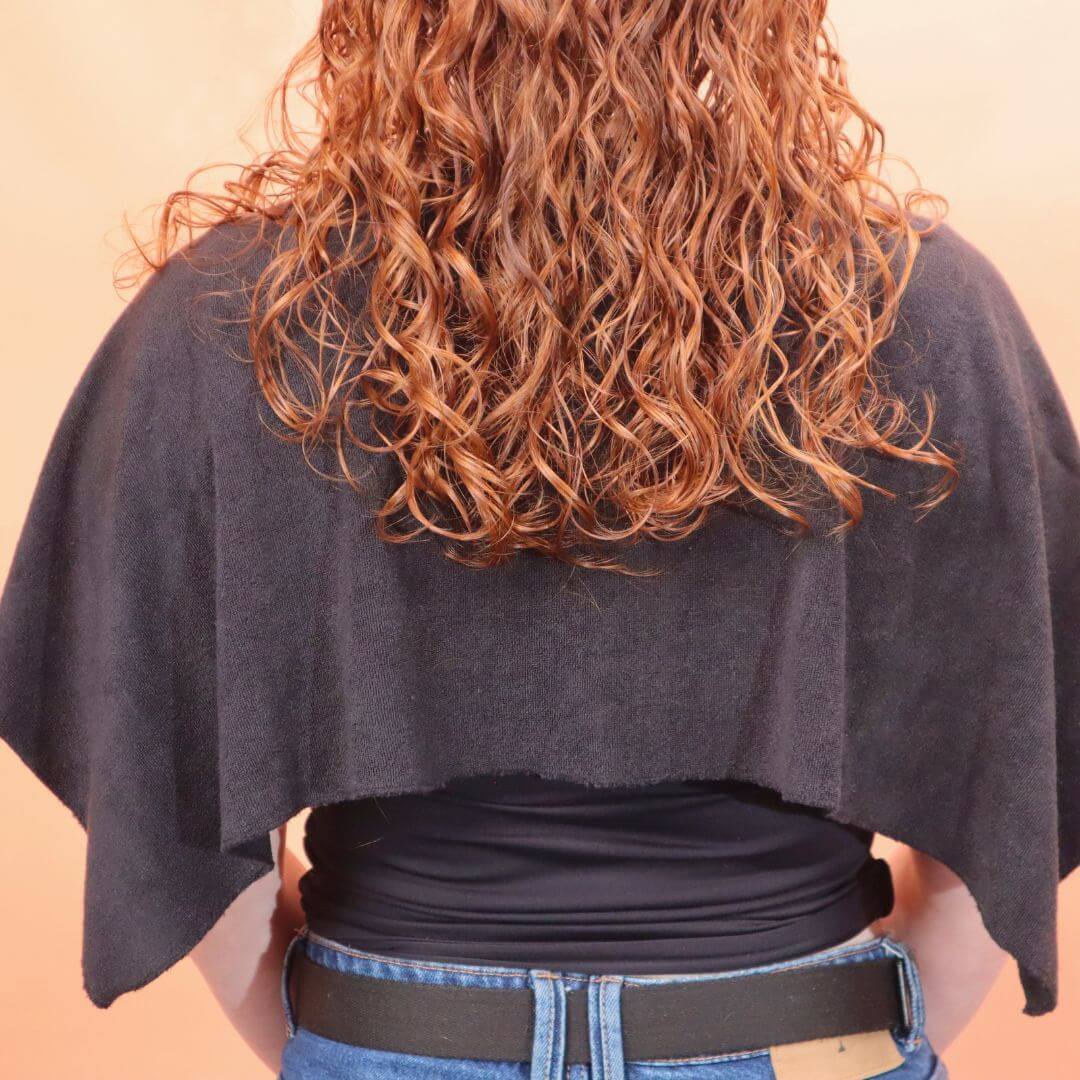 The back of a lady showing how the cold shoulder guard protects her clothes from wet curly hair