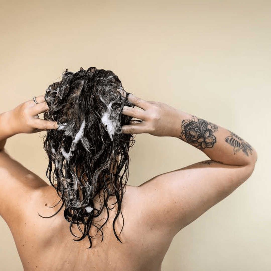 woman washing shoulder length curly brunette hair