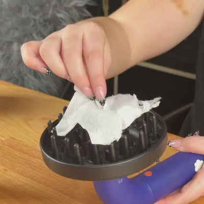 hair dryer with black diffuser attachment blowing away tissue